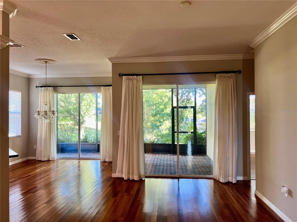 A living area with hardwood floors, two sliding glass doors, and a screened-in patio — 119 FALLING ACORN AVENUE, GROVELAND, FL