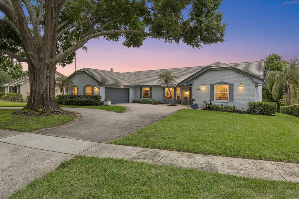 A single-story house with a gray brick exterior, a tile roof, and a large front tree — 8606 LOST COVE DRIVE, ORLANDO, FL