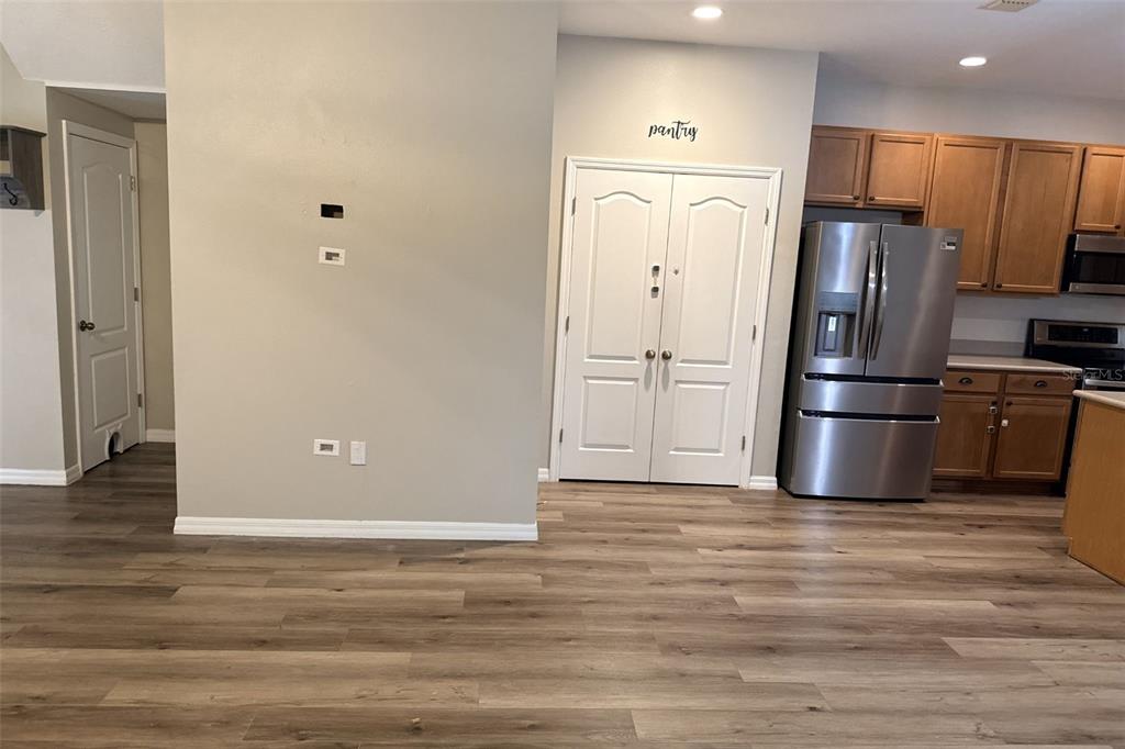 A kitchen features wood cabinets, stainless steel appliances, and light wood-look flooring — 5573 RUTHERFORD PLACE, OVIEDO, FL