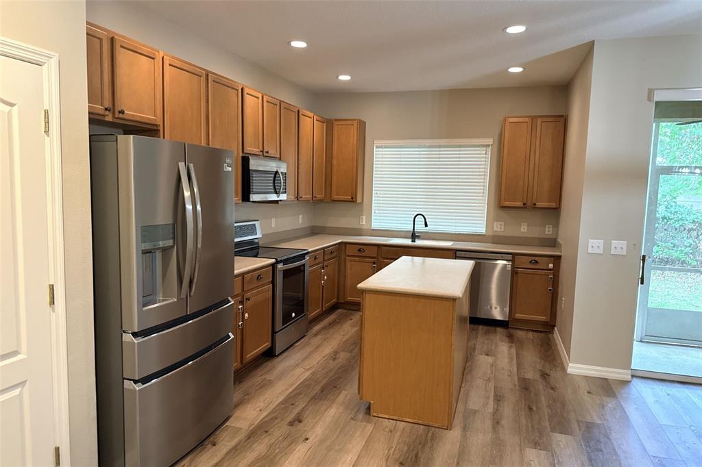 An empty bedroom features light brown walls, white baseboards, and dark wood-look flooring — 5573 RUTHERFORD PLACE, OVIEDO, FL