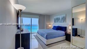 A bedroom with a king bed, a floor lamp, and a balcony overlooking the ocean — 6365 Collins Ave # 3802, Miami Beach FL 33141, MIAMI BEACH, FL