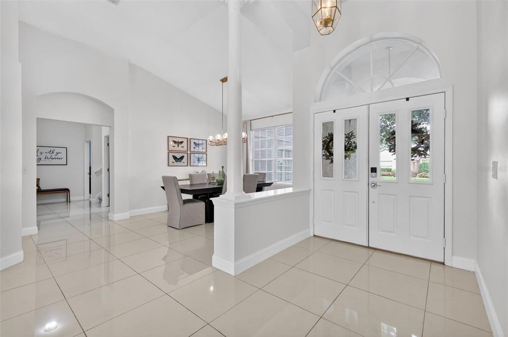 A bright foyer with white tile floors leads to a dining area with a central column — 9041 LAUREL RIDGE DRIVE, MOUNT DORA, FL