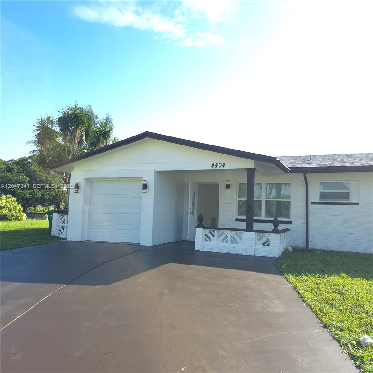A single-story white house features a garage, a front porch, and a paved driveway — 4404 NW 46th Way, Tamarac FL 33319, TAMARAC, FL