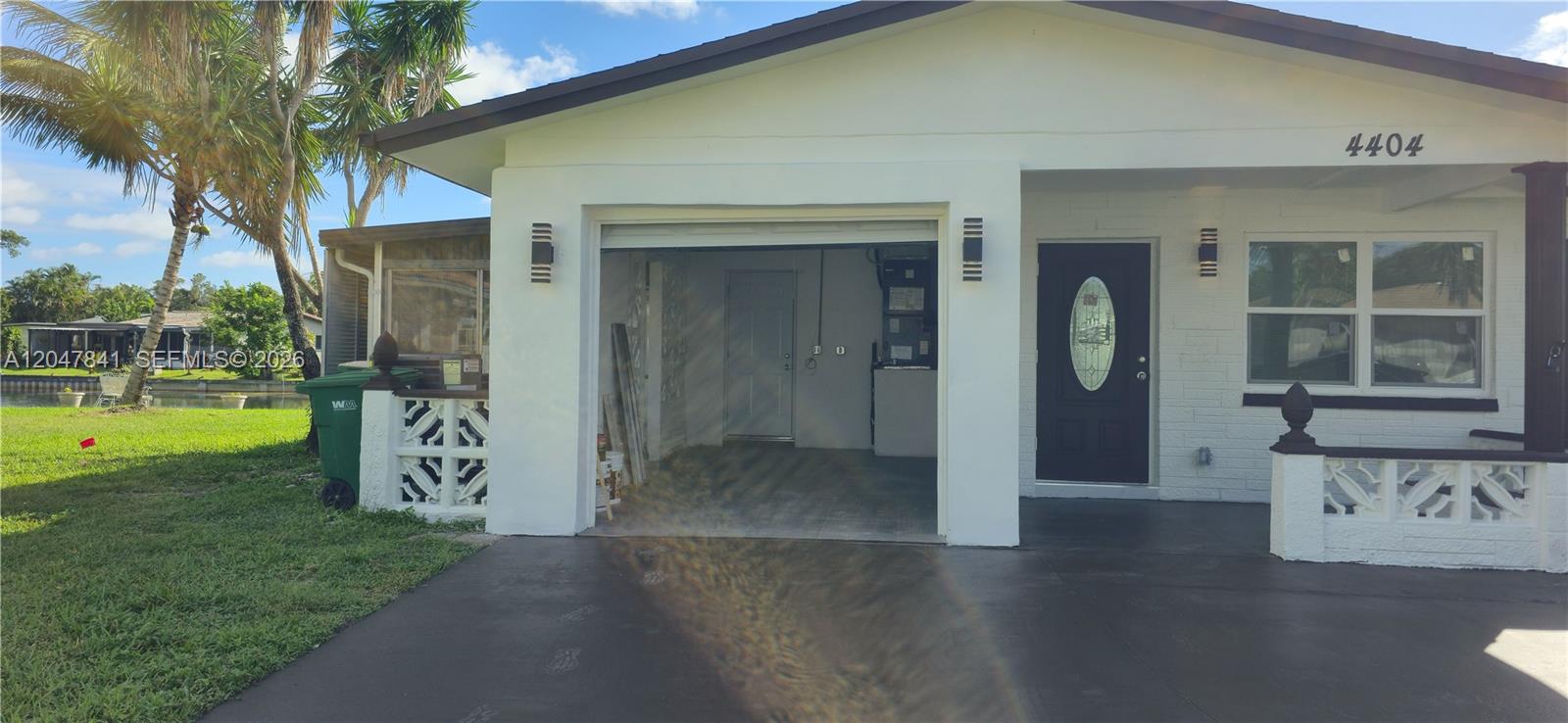A white house exterior features a garage, a dark front door, and a paved driveway — 4404 NW 46th Way, Tamarac FL 33319, TAMARAC, FL