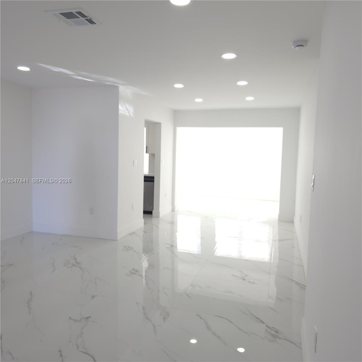 A bright, empty room features white walls, recessed lighting, and polished white marble-patterned tile flooring — 4404 NW 46th Way, Tamarac FL 33319, TAMARAC, FL