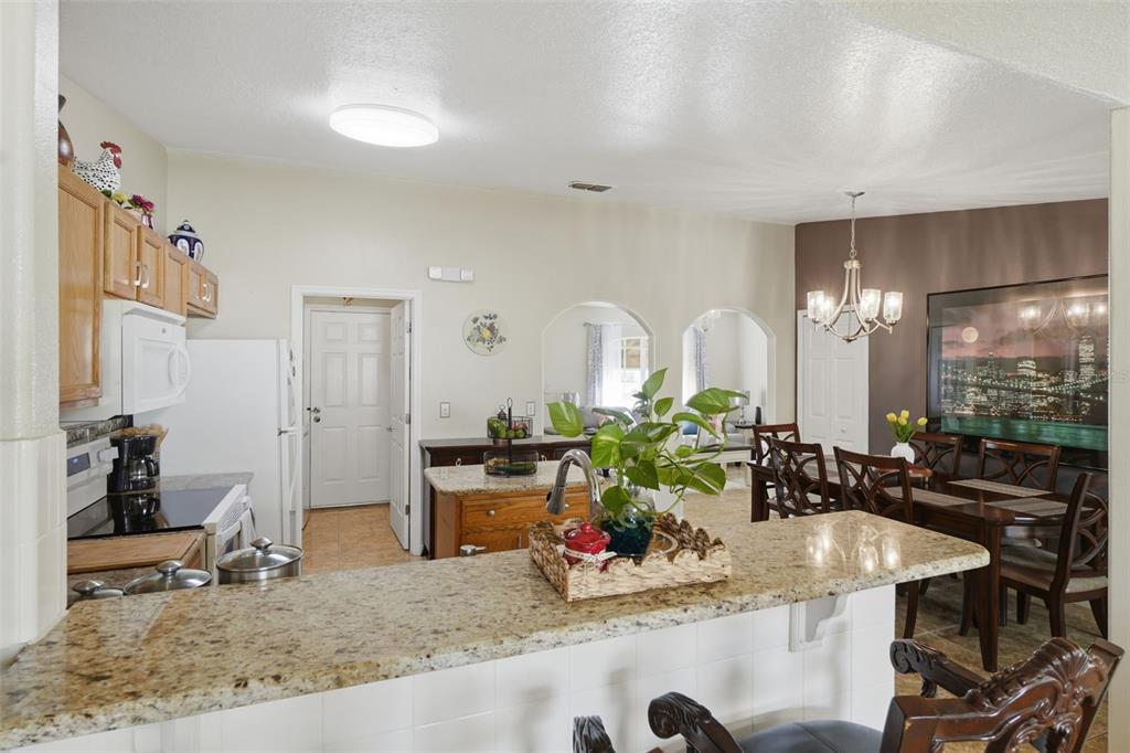 A kitchen with granite countertops and a breakfast bar overlooks a dining area — 1029 DUDLEY DRIVE, KISSIMMEE, FL