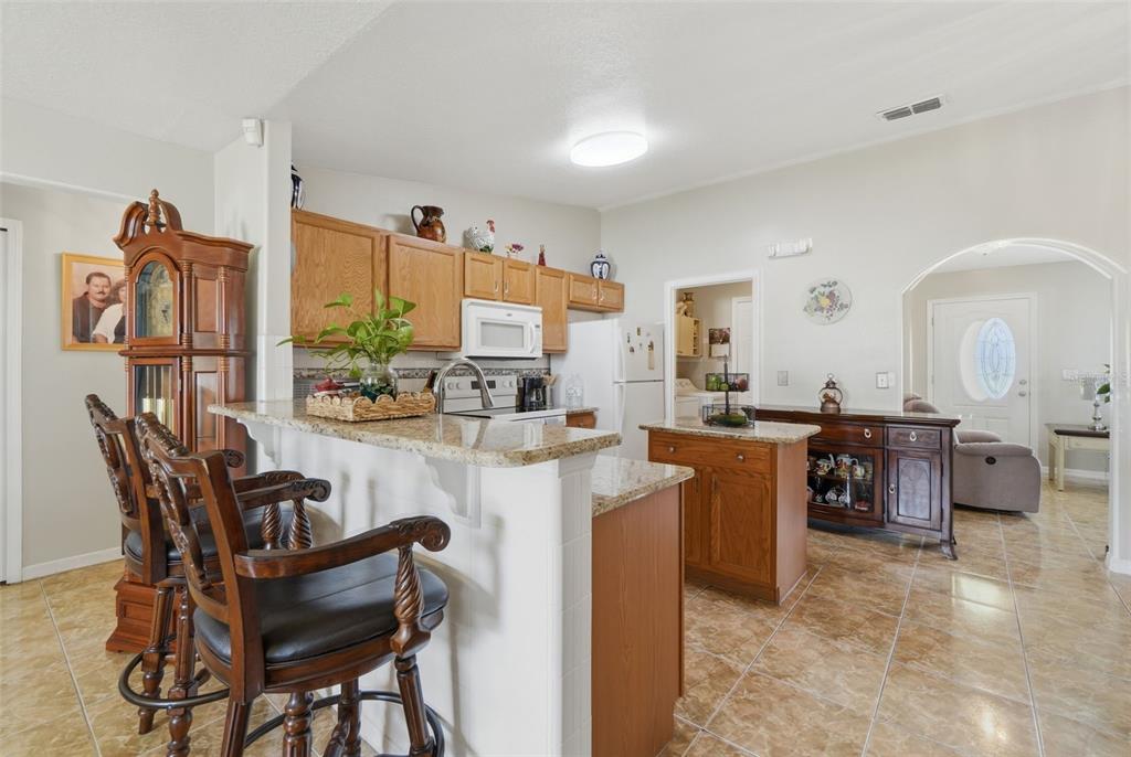 A kitchen features oak cabinets, granite countertops, a breakfast bar, and tile flooring — 1029 DUDLEY DRIVE, KISSIMMEE, FL