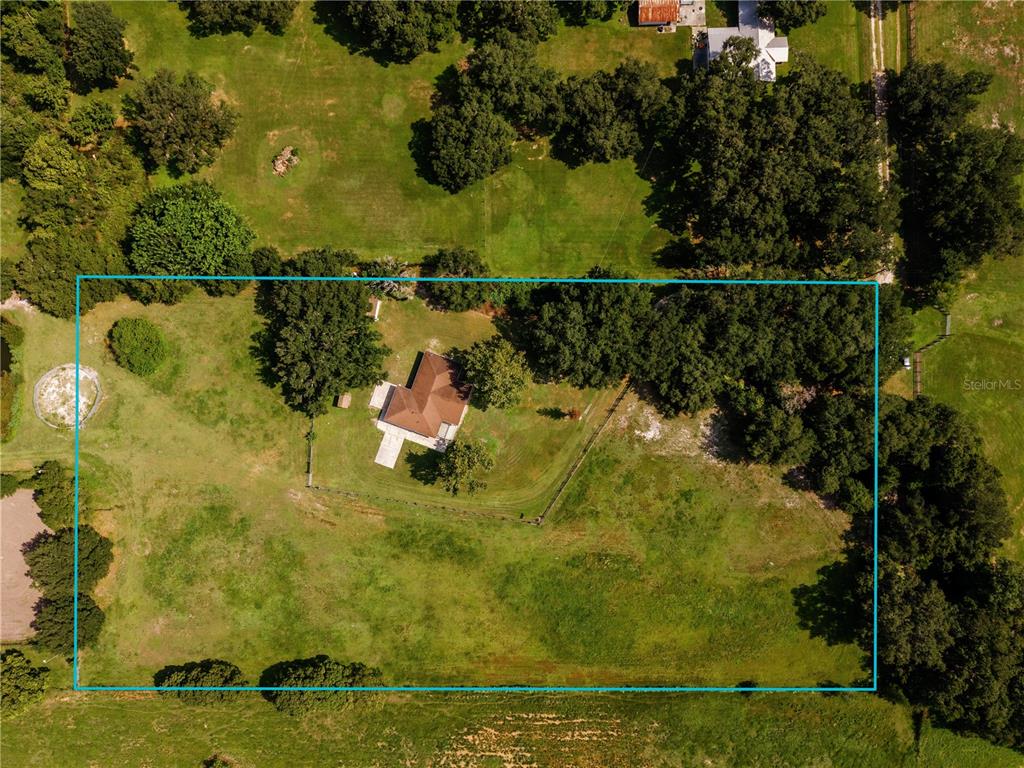 An aerial view shows a house situated on a large, fenced, grassy rural lot — 3430 WESTSHORE DRIVE, ST CLOUD, FL