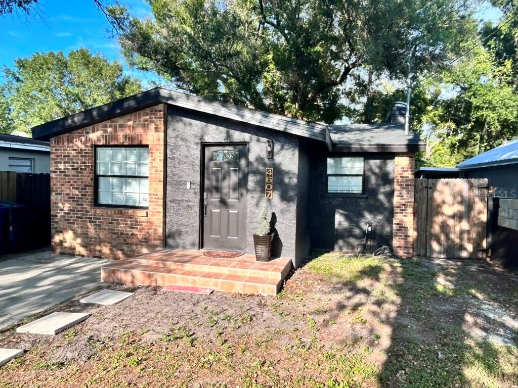 A single-story house features a brick and dark stucco exterior with a tiled front porch — 4607 N 35TH STREET, TAMPA, FL
