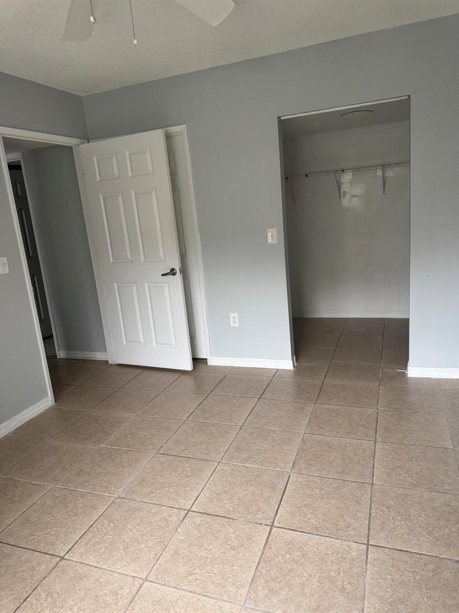 A bedroom with light gray walls, tiled flooring, an open closet, and a white door — 1670 N 42nd Circle # 105, Vero Beach FL 32967, VERO BEACH, FL