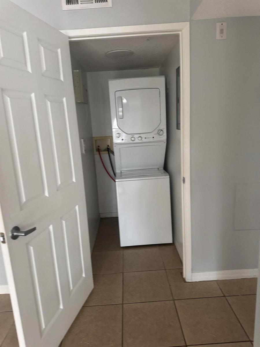 A laundry closet contains a stacked white washer and dryer unit on a tiled floor — 1670 N 42nd Circle # 105, Vero Beach FL 32967, VERO BEACH, FL
