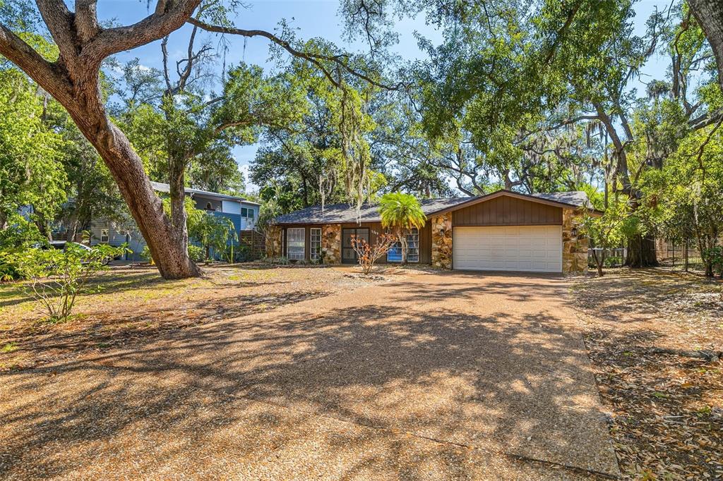 A single-story house with a stone facade, a two-car garage, and large oak trees — 2749 GREENDALE DRIVE, SARASOTA, FL