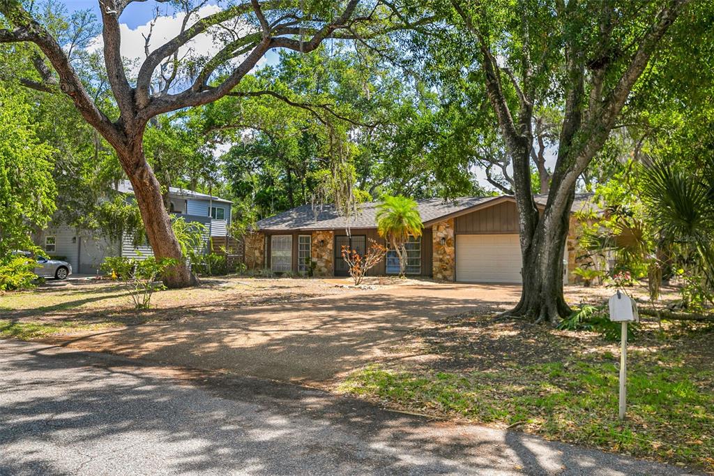 A single-story house with a stone facade, a two-car garage, and large trees in front — 2749 GREENDALE DRIVE, SARASOTA, FL