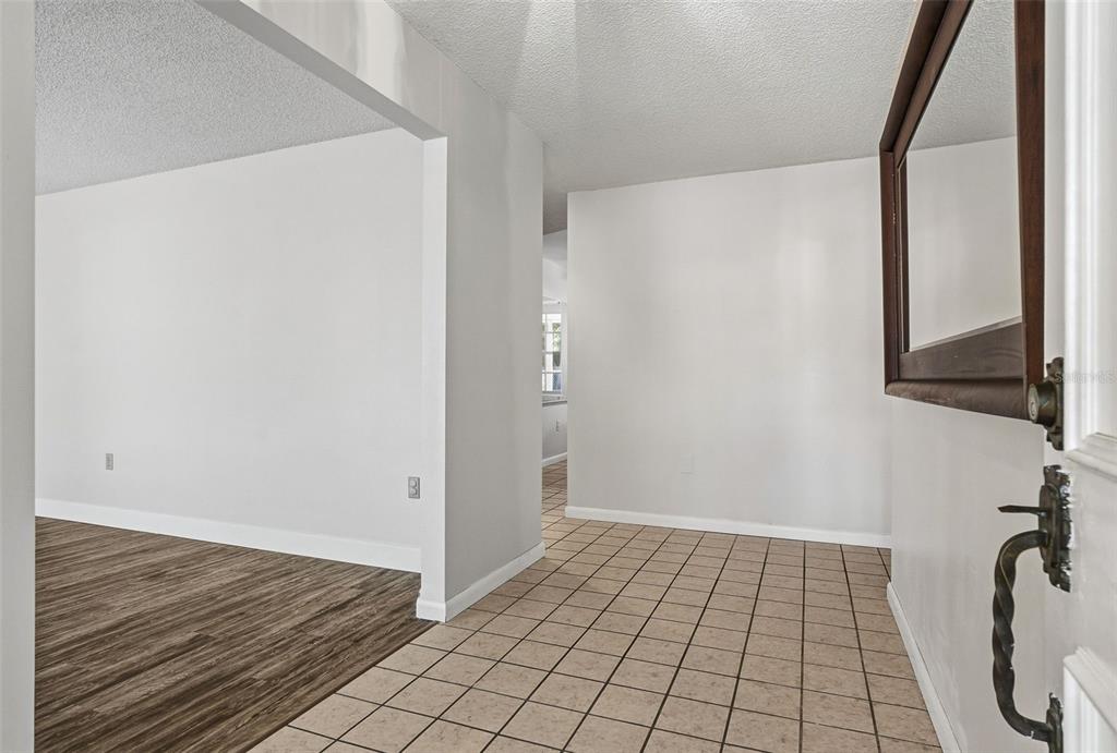 An entryway with tan tile flooring leads into a living area with wood-look flooring — 2749 GREENDALE DRIVE, SARASOTA, FL