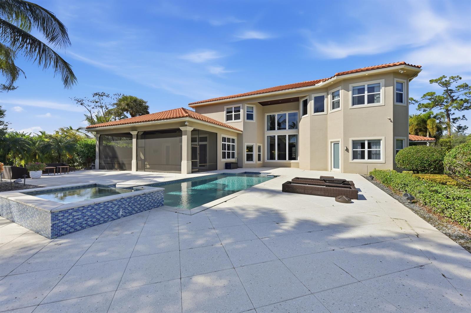 The exterior of a two-story house features a swimming pool, a hot tub, and a patio — 13550 Greentree Trail, Wellington FL 33414, WELLINGTON, FL