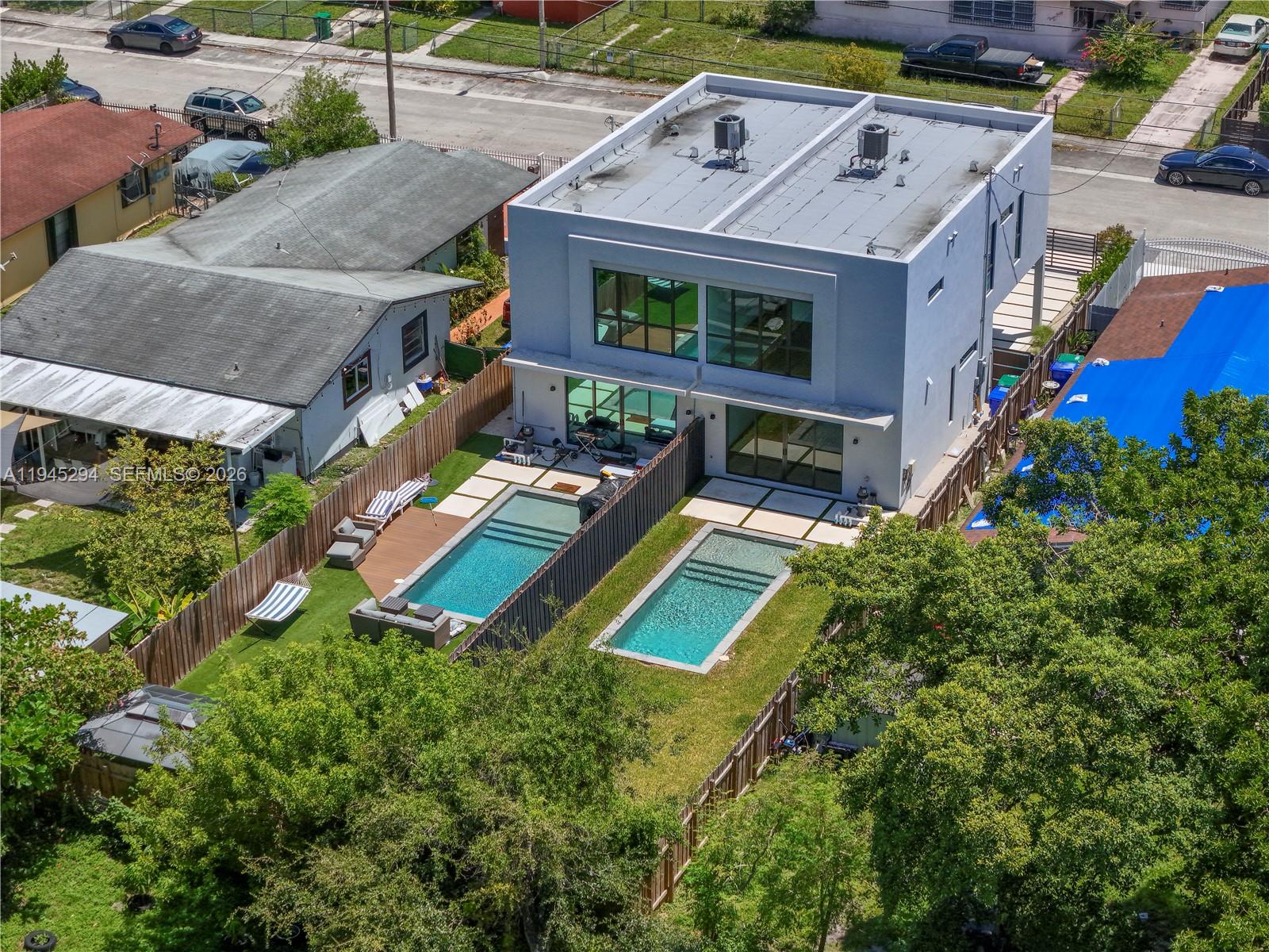 An aerial view shows a modern two-story house with two separate swimming pools in the backyard — 355 NW 50th St, Miami FL 33127, MIAMI, FL