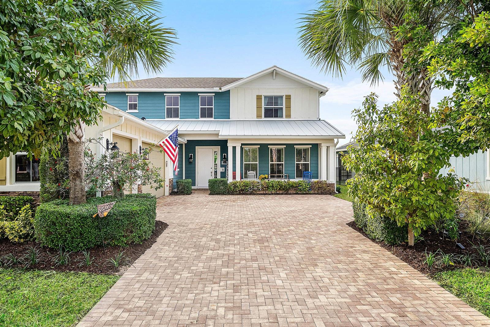 A two-story house with blue and white siding features a brick paver driveway and landscaping — 1107 Timber Reap Trail, Loxahatchee FL 33470, LOXAHATCHEE, FL