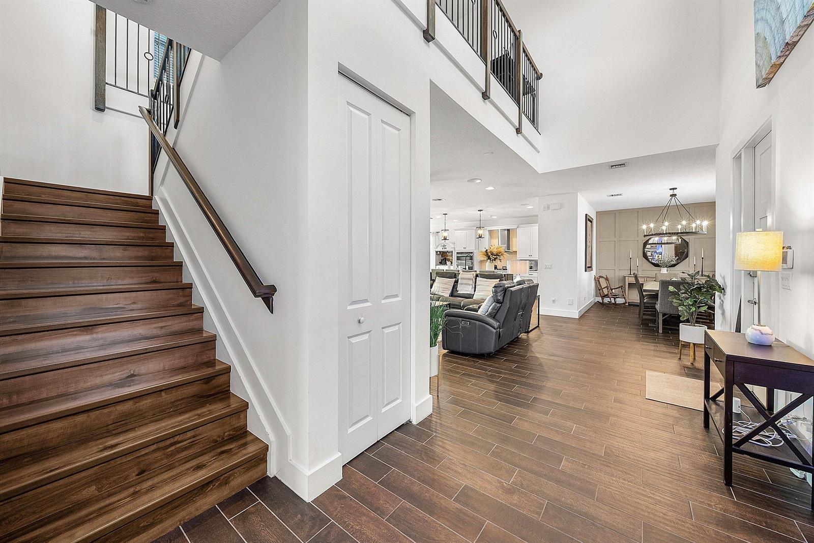 A foyer with wood-look tile floors leads to a staircase and an open-concept living area — 1107 Timber Reap Trail, Loxahatchee FL 33470, LOXAHATCHEE, FL