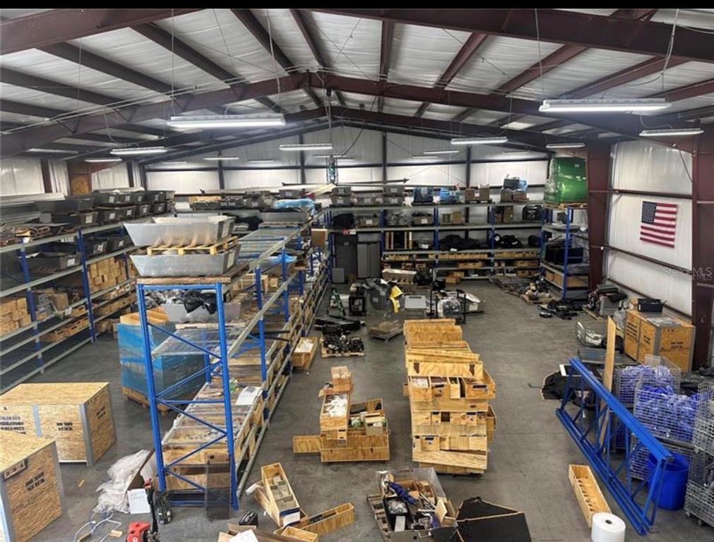An interior view of a large industrial warehouse featuring metal shelving units and wooden crates — 1721 LEESBURG COMMONS COURT, LEESBURG, FL