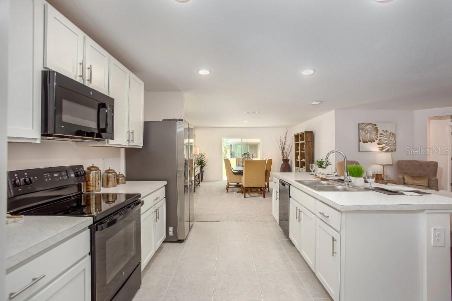 A kitchen with white cabinets, stainless steel appliances, and an island overlooking a dining area — 25290 PUERTA DRIVE, PUNTA GORDA, FL