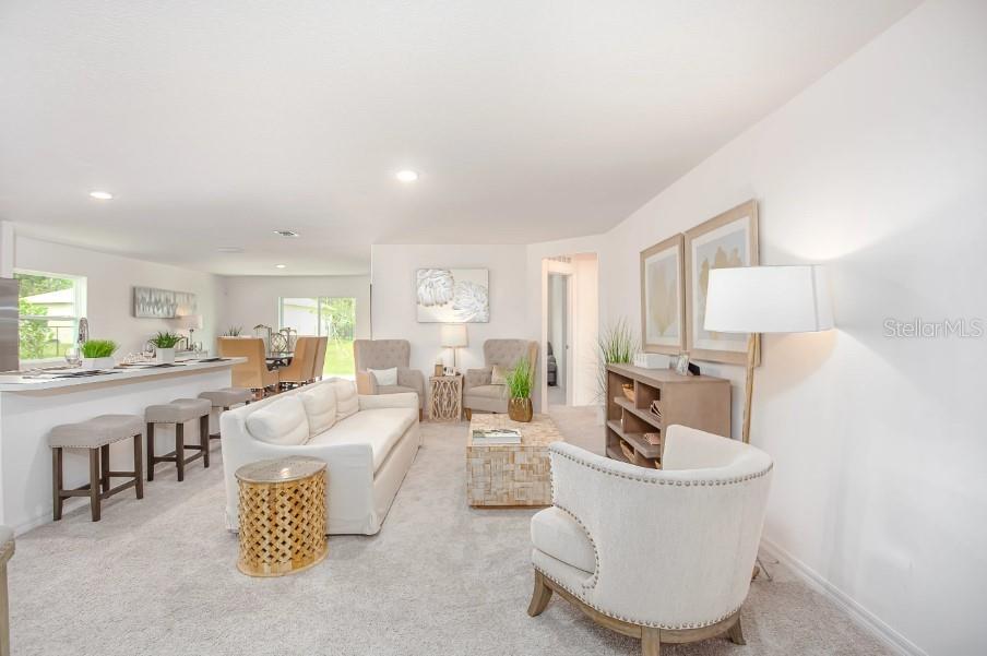 A bright living room features a white sofa, neutral armchairs, and a kitchen breakfast bar — 25290 PUERTA DRIVE, PUNTA GORDA, FL