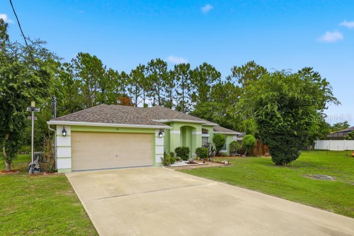 A single-story house with a light green exterior, a two-car garage, and a concrete driveway — 18 BURTON PLACE, PALM COAST, FL