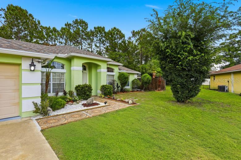 A lime green house with a decorative stone walkway and a large front yard — 18 BURTON PLACE, PALM COAST, FL