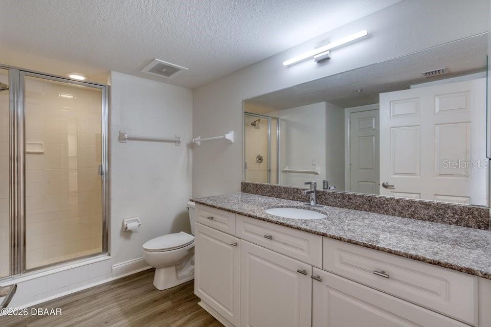 A bathroom features a granite-topped vanity, a walk-in shower, and light-colored cabinetry — 3145 S ATLANTIC AVENUE UNIT 503, DAYTONA BEACH, FL