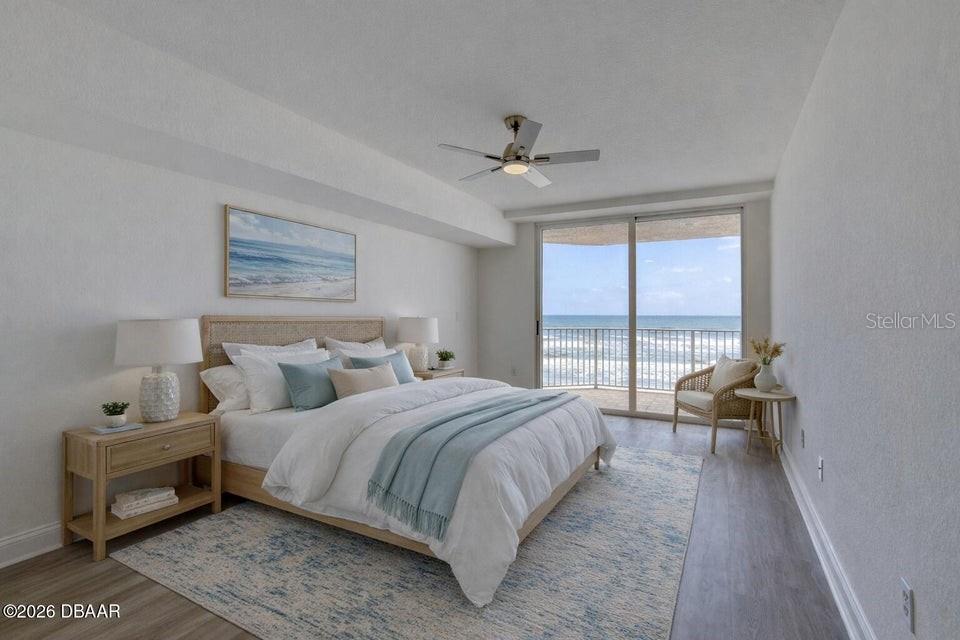 A bedroom features a bed with blue accents, a ceiling fan, and a balcony overlooking ocean — 3145 S ATLANTIC AVENUE UNIT 503, DAYTONA BEACH, FL
