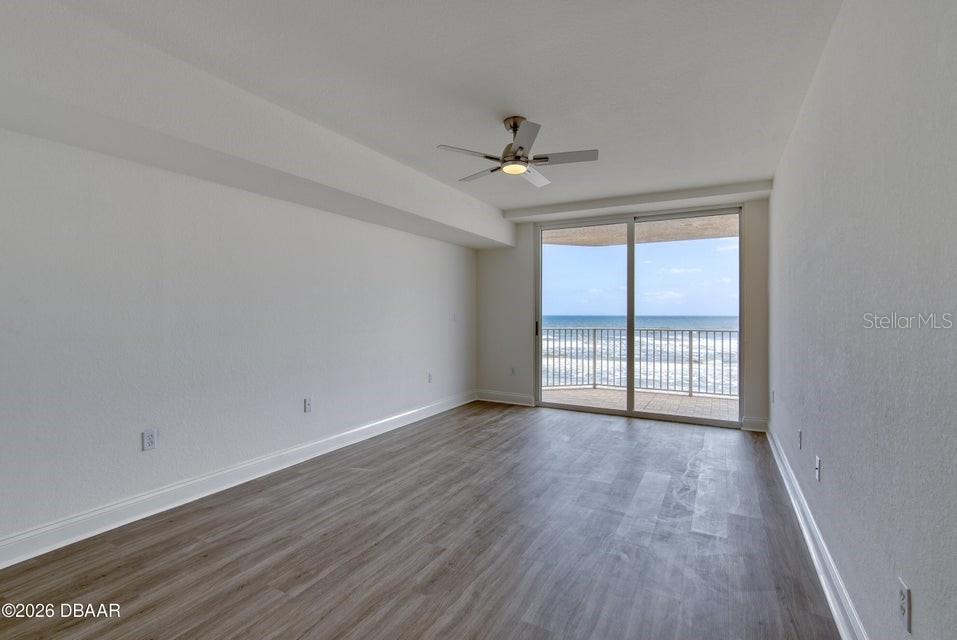 An empty room with wood-look flooring, a ceiling fan, and sliding doors leading to a balcony — 3145 S ATLANTIC AVENUE UNIT 503, DAYTONA BEACH, FL