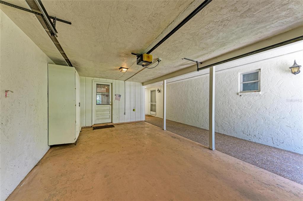 A covered carport with a concrete floor, a storage cabinet, and two exterior doors — 6905 9TH AVENUE W UNIT 6905, BRADENTON, FL