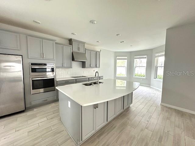 A modern kitchen features light gray cabinets, stainless steel appliances, and a large white island — 3860 ROSE MALLOW DRIVE, KISSIMMEE, FL