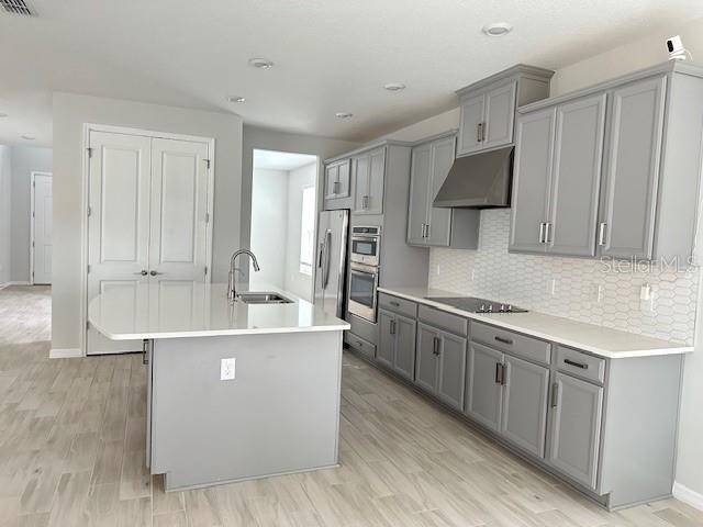A modern kitchen features gray cabinetry, a central island with a sink, and light flooring — 3860 ROSE MALLOW DRIVE, KISSIMMEE, FL