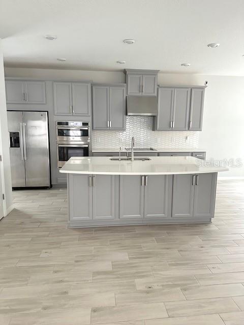 A modern kitchen features gray cabinets, stainless steel appliances, and a large white-topped island — 3860 ROSE MALLOW DRIVE, KISSIMMEE, FL