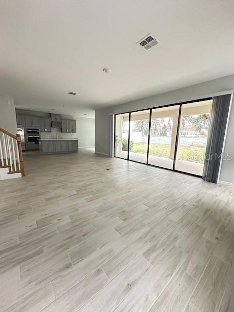 An open-concept living area features light wood-look tile flooring and large sliding glass doors — 3860 ROSE MALLOW DRIVE, KISSIMMEE, FL