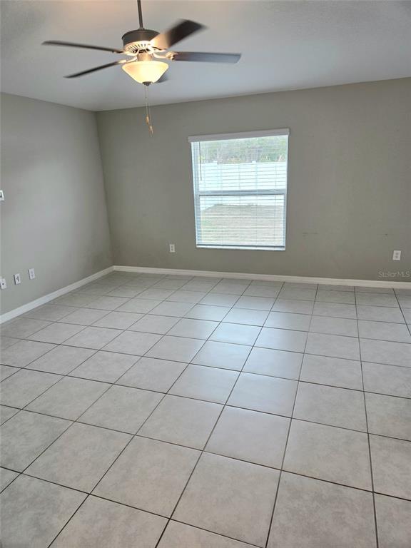 An empty room with light gray walls, large floor tiles, and a ceiling fan — 10316 SHADY PRESERVE DRIVE, RIVERVIEW, FL