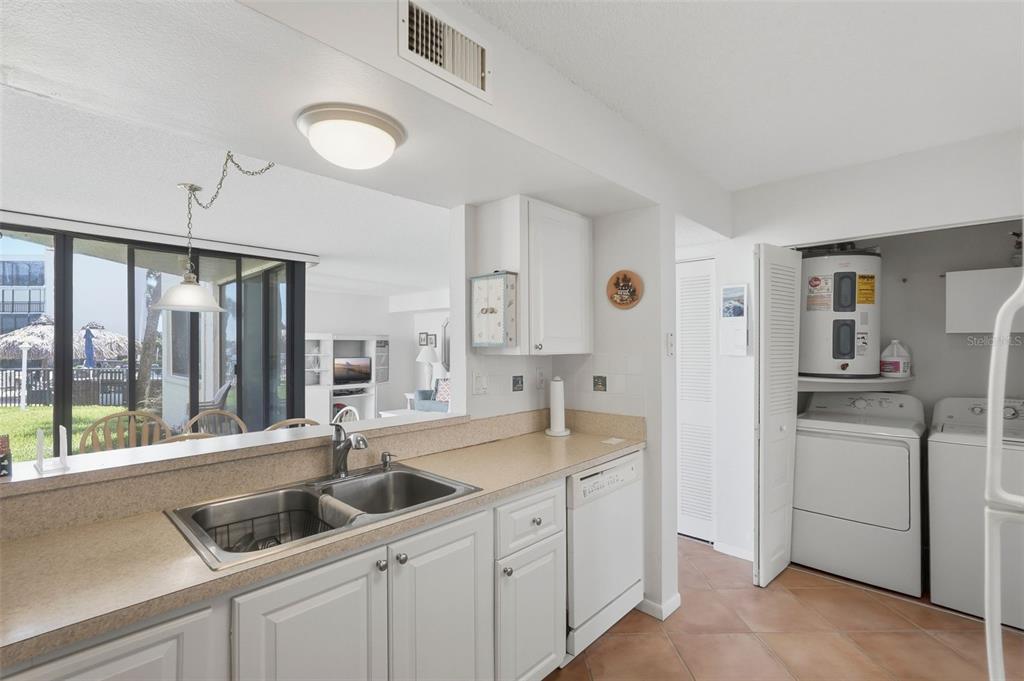 A kitchen with white cabinets, laminate countertops, and an adjacent laundry closet with appliances — 5729 PUERTA DEL SOL BOULEVARD S UNIT 186, ST PETERSBURG, FL