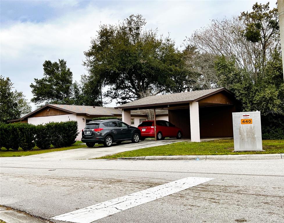 A single-story house with a carport and two parked cars sits behind a utility box — 366 DIAMOND STREET, DELTONA, FL