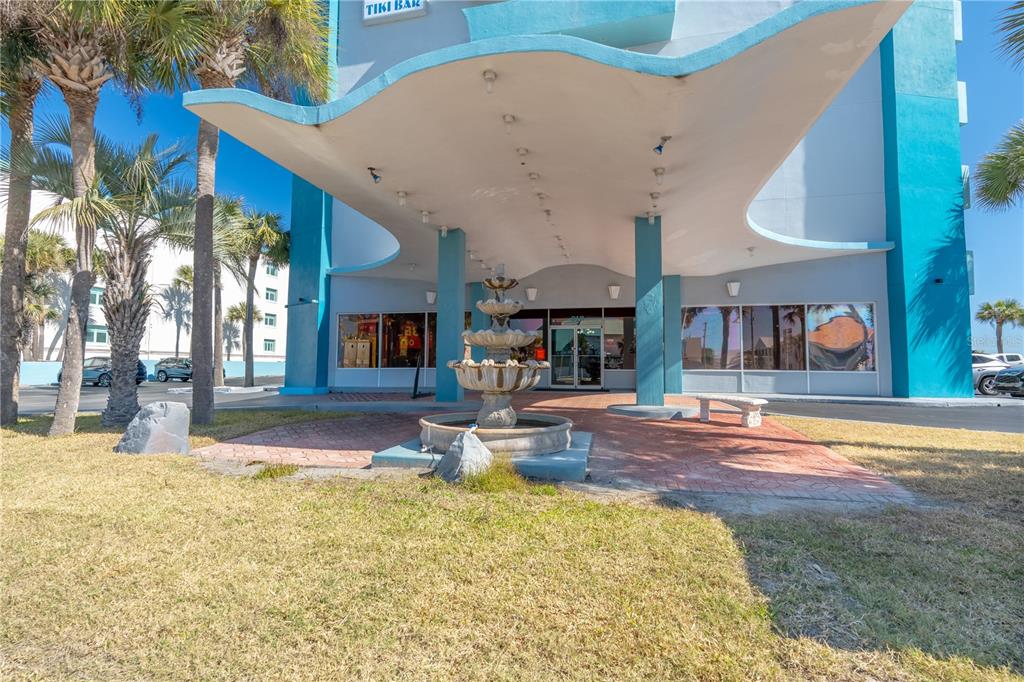A multi-tiered fountain sits under a large, curved overhang in front of a blue building — 313 S ATLANTIC AVENUE UNIT 4250, DAYTONA BEACH, FL
