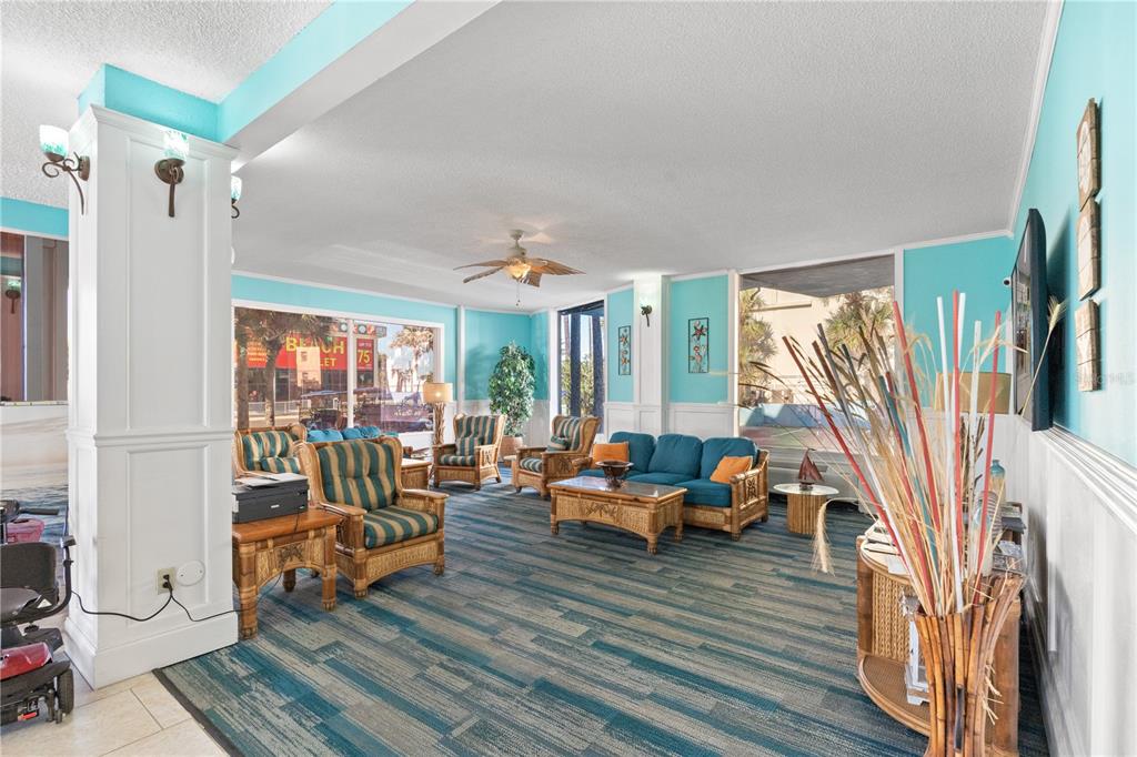 A lobby area features teal walls, wicker furniture, a blue sofa, and patterned carpet flooring — 313 S ATLANTIC AVENUE UNIT 4250, DAYTONA BEACH, FL