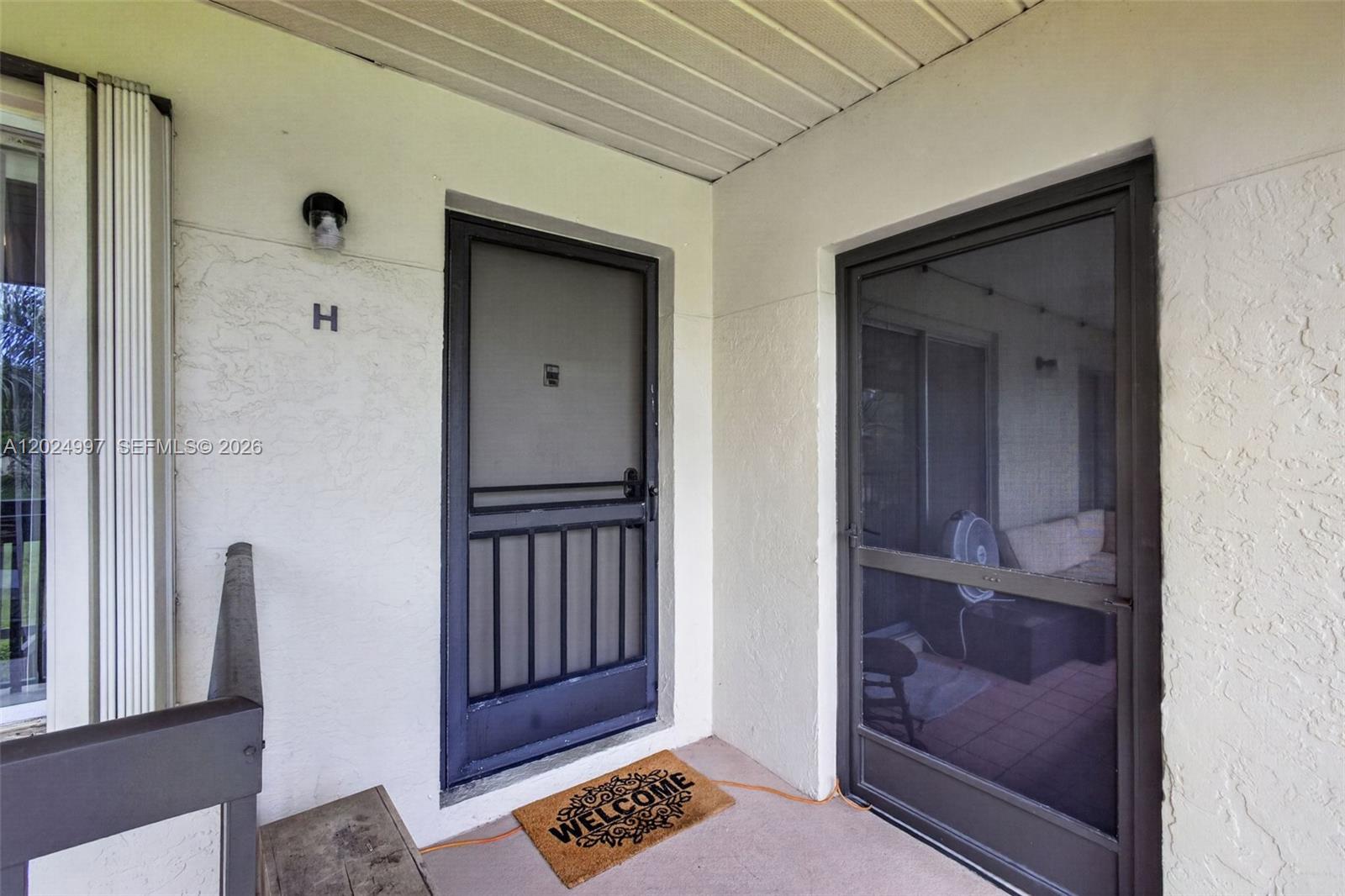 This exterior view shows a covered entryway with two screen doors and a welcome mat — 6555 Chasewood Dr # H, Jupiter FL 33458, JUPITER, FL