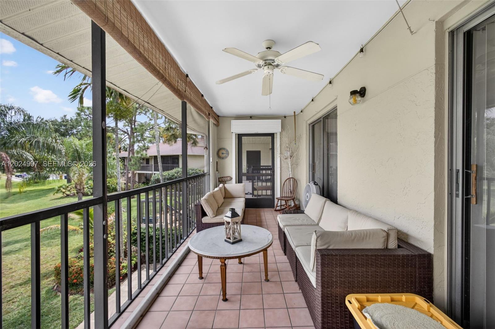 A covered balcony features tiled flooring, wicker patio furniture, a ceiling fan, and metal railings — 6555 Chasewood Dr # H, Jupiter FL 33458, JUPITER, FL