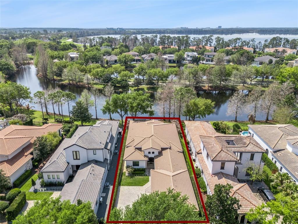 An aerial view shows a house with a tiled roof outlined in red near water — 10228 KENSINGTON SHORE DRIVE, ORLANDO, FL
