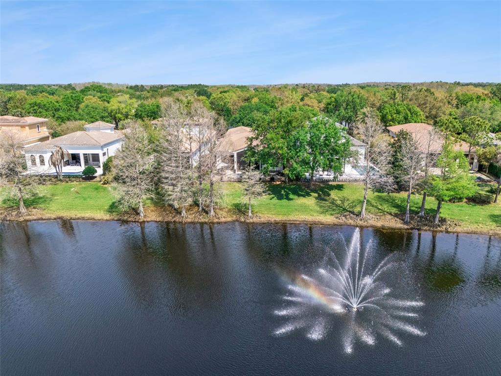 An aerial view shows several houses situated along a lake with a large water fountain — 10228 KENSINGTON SHORE DRIVE, ORLANDO, FL