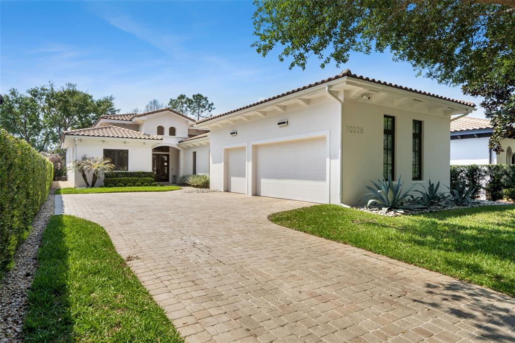 A single-story white house with a tile roof and a paved driveway — 10228 KENSINGTON SHORE DRIVE, ORLANDO, FL