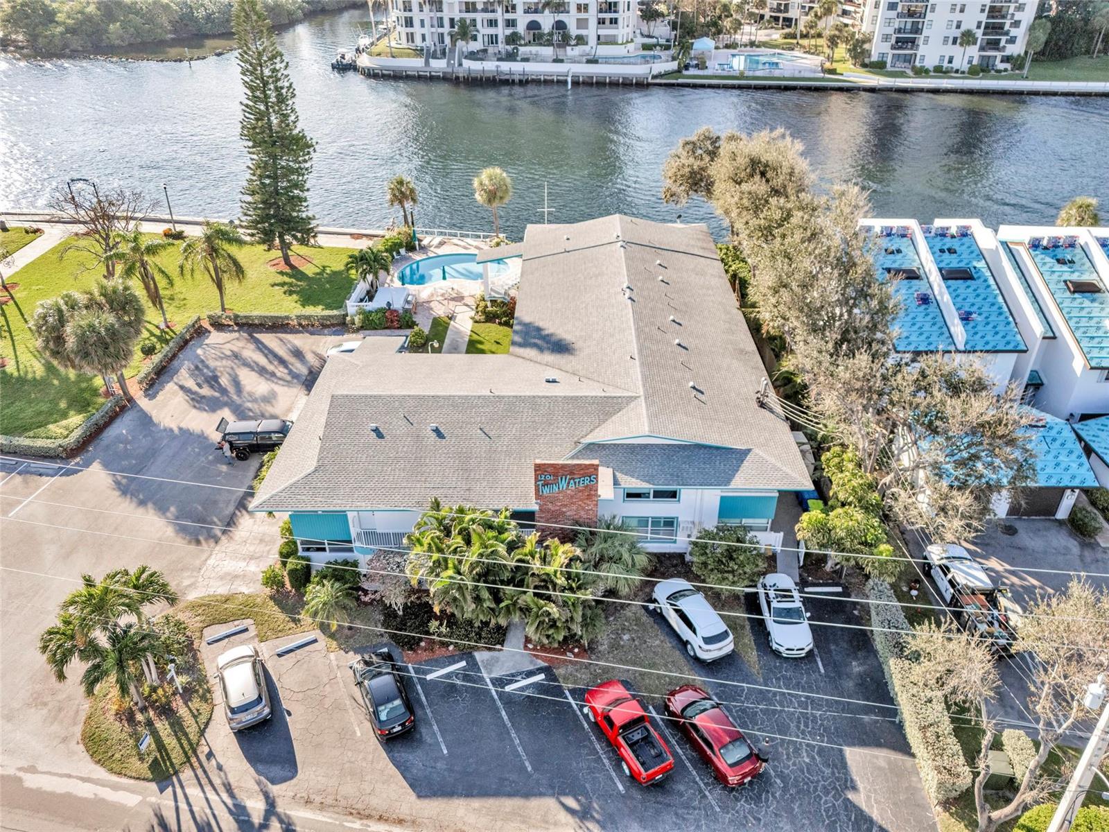 An aerial view shows a multi-story building with a pool, parking lot, and waterfront access — 1201 N Riverside Drive # 12b, Pompano Beach FL 33062, POMPANO BEACH, FL