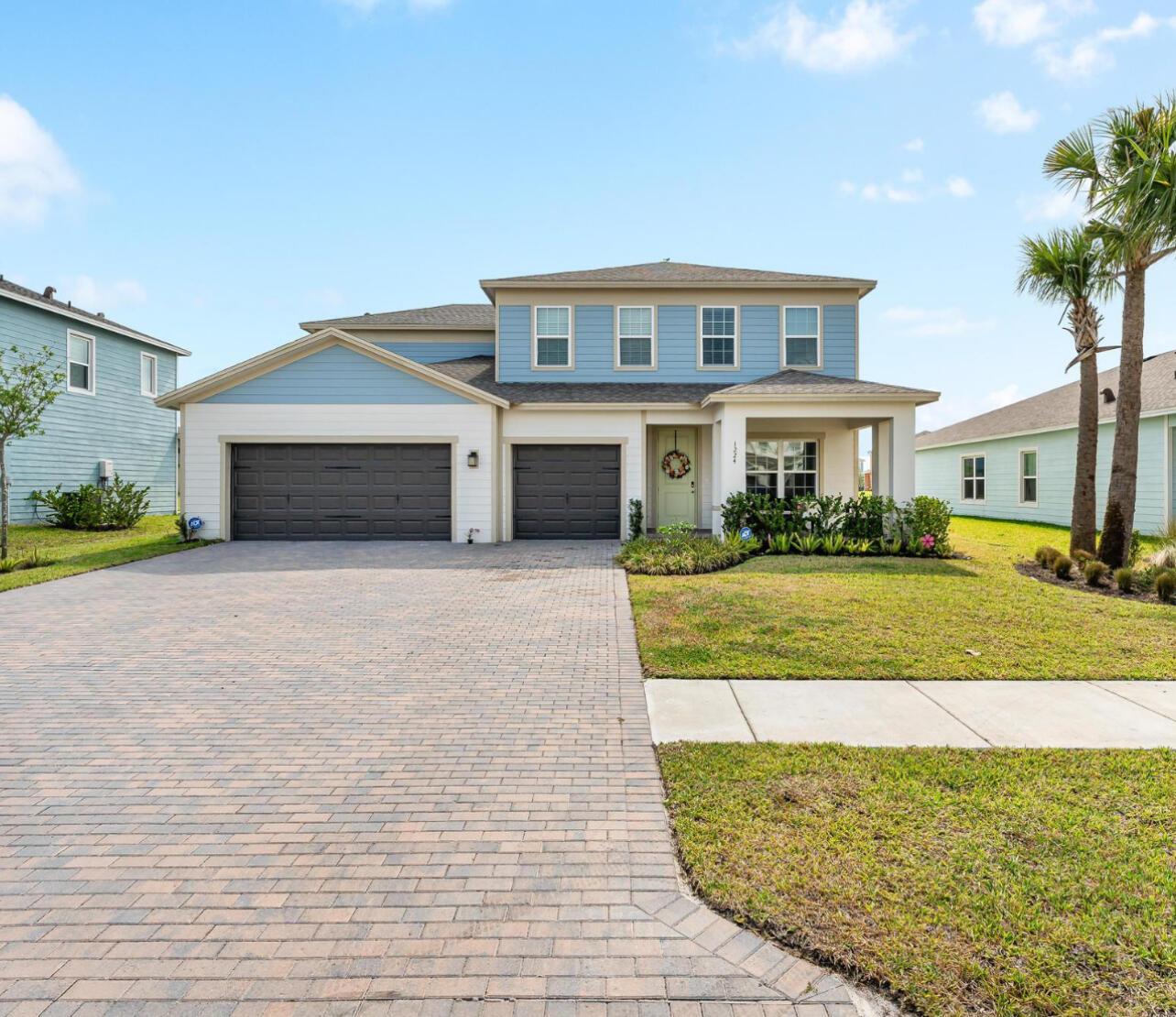 A two-story house with blue and white siding, a brick driveway, and a three-car garage — 1224 Harvester Crossing, Loxahatchee FL 33470, LOXAHATCHEE, FL