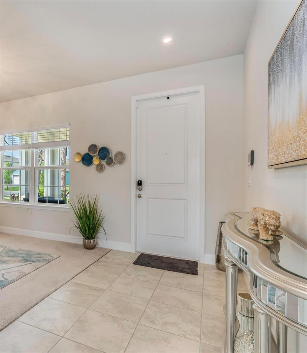 An entryway features a white door, tiled floor, a mirrored console table, and wall art — 1224 Harvester Crossing, Loxahatchee FL 33470, LOXAHATCHEE, FL