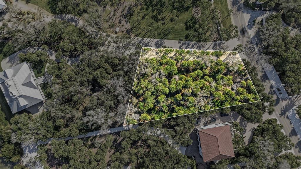 An aerial view shows a vacant, wooded residential lot outlined in white between two houses — MANASOTA KEY ROAD, ENGLEWOOD, FL