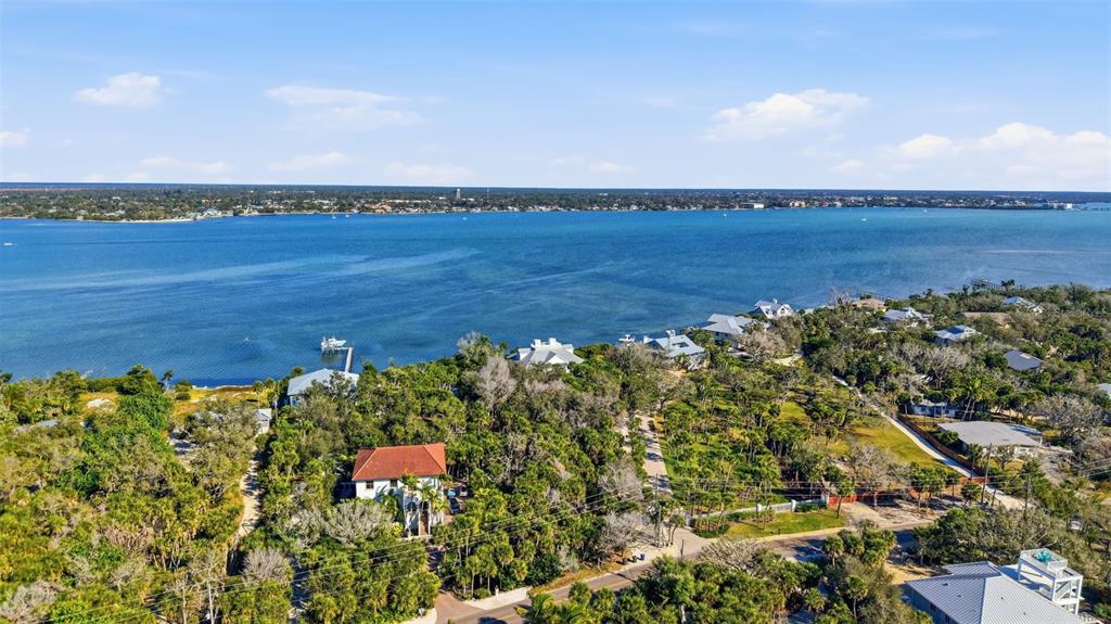 An aerial view shows a coastal neighborhood with houses nestled among trees near the water — MANASOTA KEY ROAD, ENGLEWOOD, FL